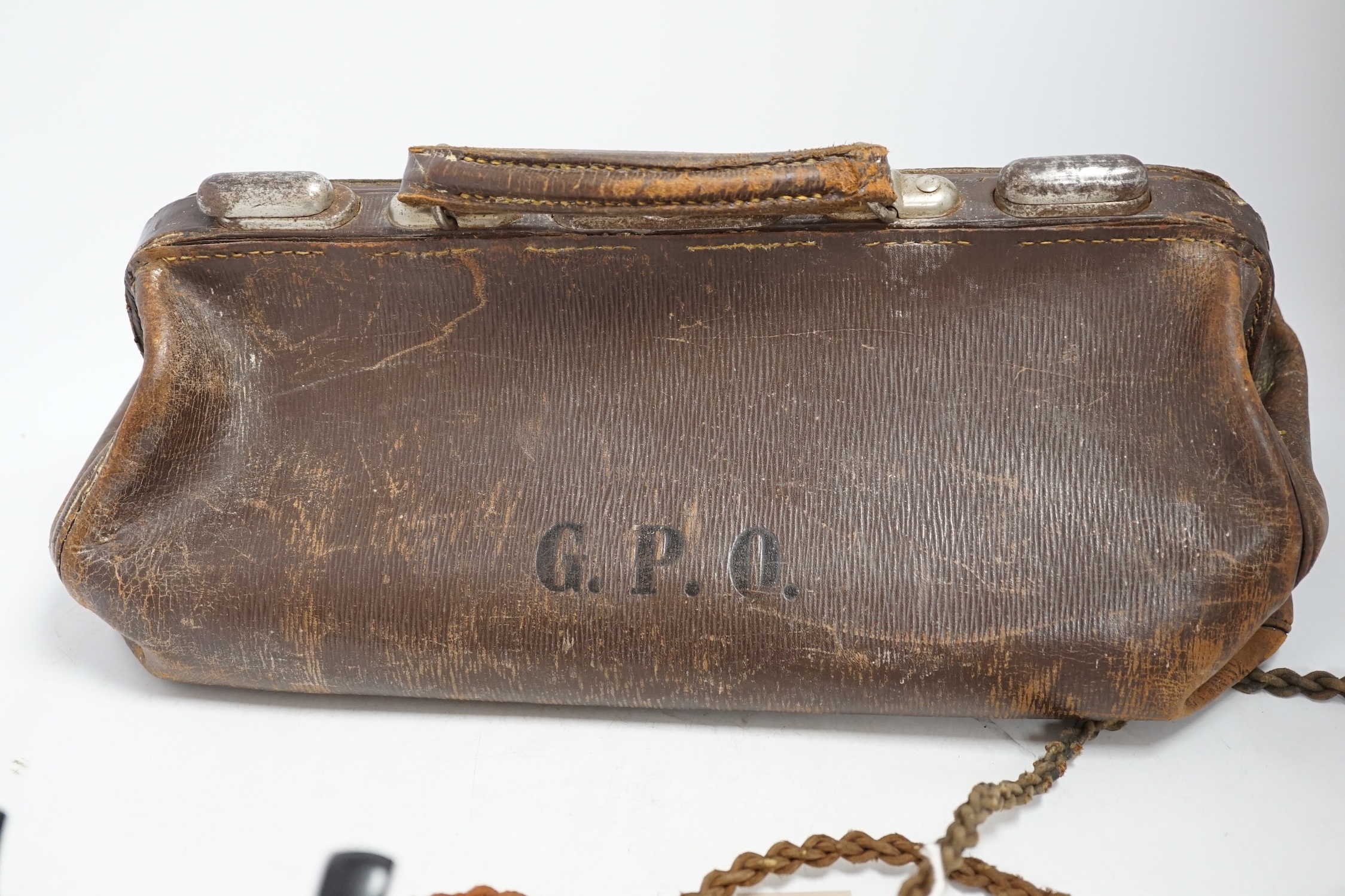A brown leather Gladstone bag with a G.P.O. stamp and a pyramid-shaped black Bakelite telephone stamped G.P.O. Condition - poor